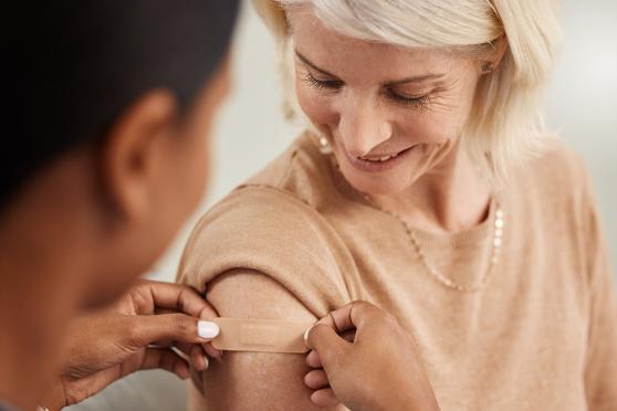 Doctor putting a bandaid on a women who just got a shot